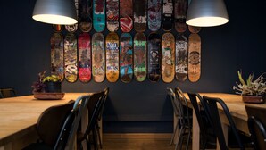 A dining area with a long wooden table, black chairs, and two pendant lights. - Sant Jordi Hostels Sagrada Familia (Barcelona)