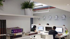 A modern workspace with white desks, computers, and a bookshelf with books. - Sant Jordi Hostels Sagrada Familia (Barcelona)