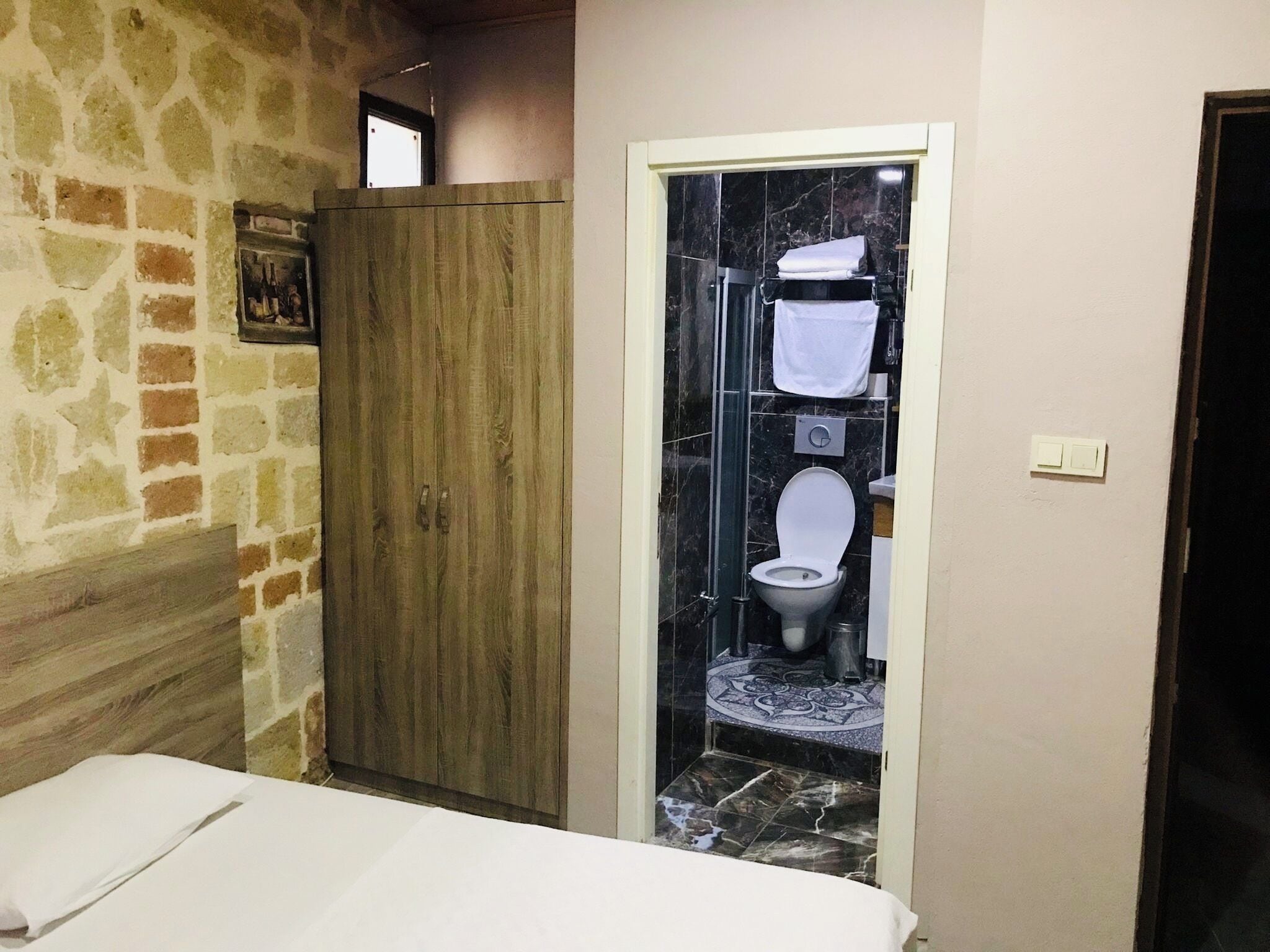 A bathroom with a toilet, a shower, and a wooden wardrobe.