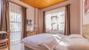 A bedroom with a bed, a TV on a stand, and a window with curtains. - Sun Anatolia Otel (Antalya)