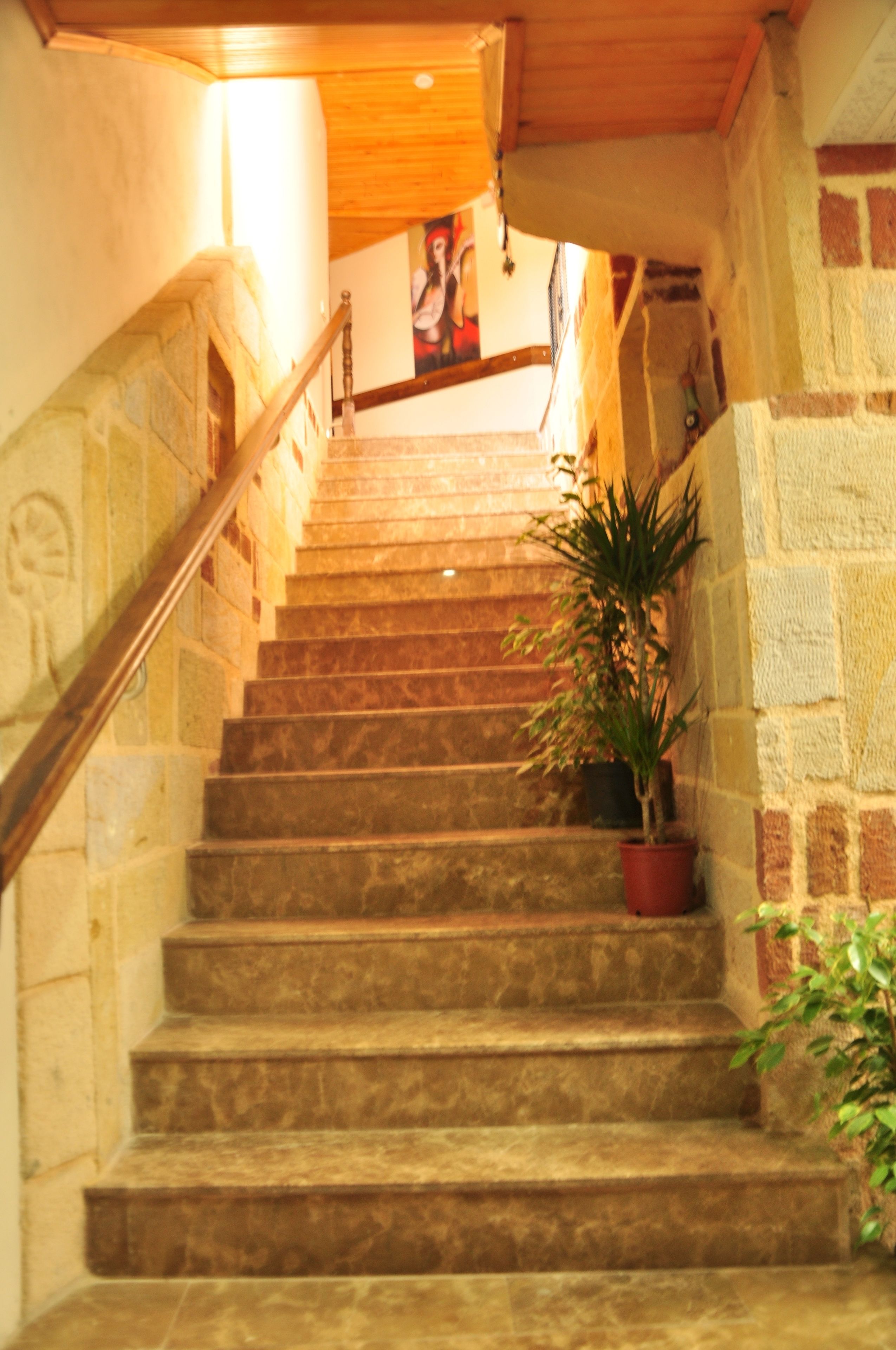 A stone staircase with a wooden handrail leading to a landing.