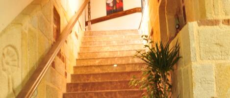 A stone staircase with a wooden handrail leading to a landing.
