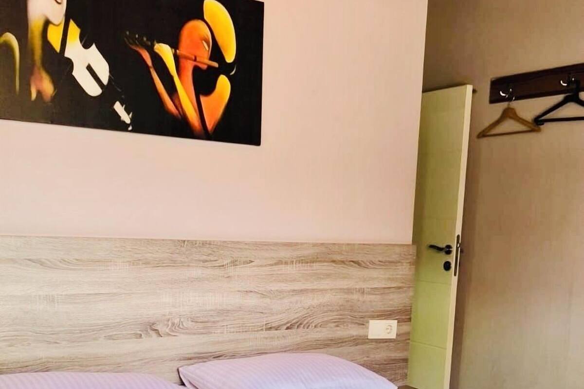 A bedroom with a bed, a wooden headboard, a wall-mounted artwork, and a door.