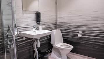 Un bagno moderno con una parete in marmo, un lavabo bianco, un water, un asciugamani ad aria e un cestino.