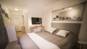 A hotel room with a large bed, a desk with a flat-screen TV, a mirror, and a refrigerator. - Hotell Tunapark (Eskilstuna)