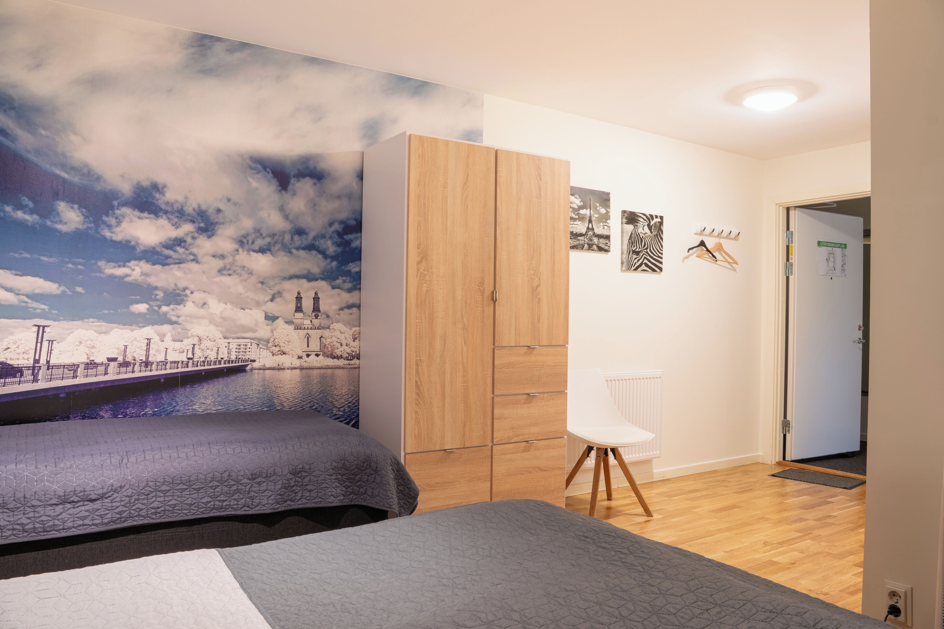 Une chambre à coucher comprenant un lit, une armoire, une chaise et une décoration murale.