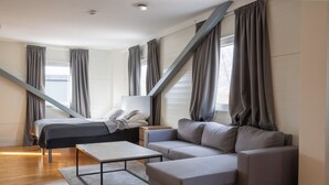 A modern bedroom with a bed, sofa, and a small table. - Hotell Tunapark (Eskilstuna)