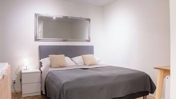 A bedroom with a bed, nightstand, and a mirror on the wall.