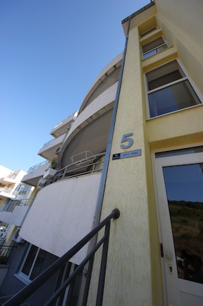 Un edificio de varios pisos con balcones y una puerta de acceso visible.