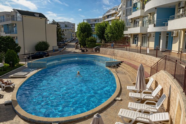 A swimming pool with lounge chairs and a stone wall. - Menada Sunset II Kosharitsa (Kosharitsa)