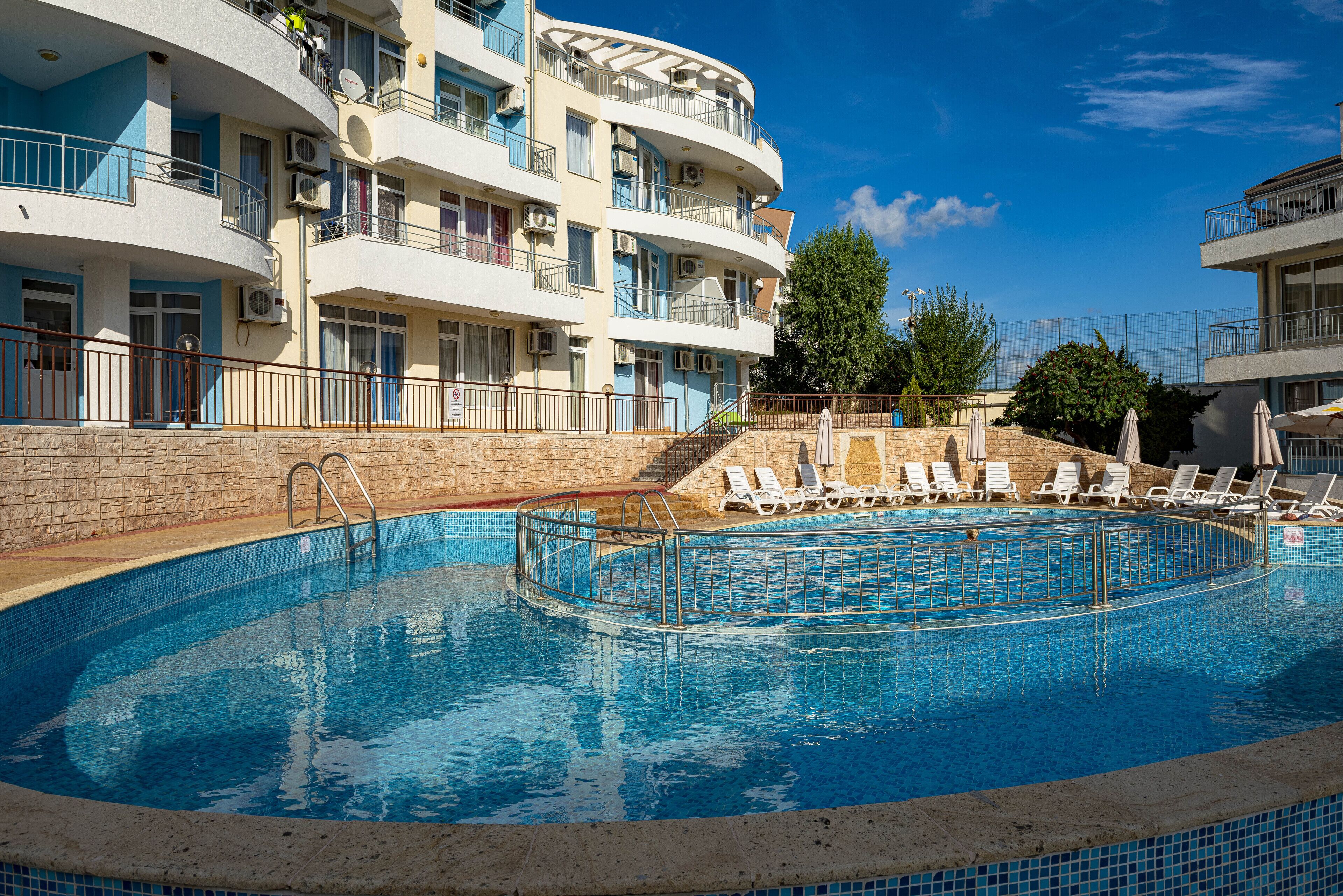 Una piscina con sillas de descanso y un muro de piedra.