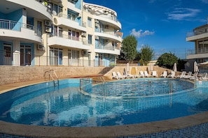 Una piscina con sillas de descanso y un muro de piedra.
