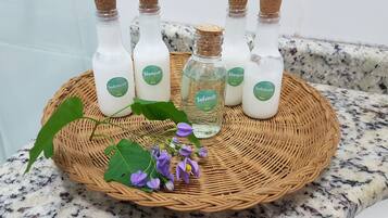 Uma bandeja de vime com garrafas de shampoo e condicionador sobre uma bancada de granito.