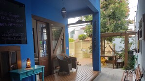 A cozy outdoor seating area with wooden furniture and a blue wall. - Solar das Pétalas (Florianópolis)