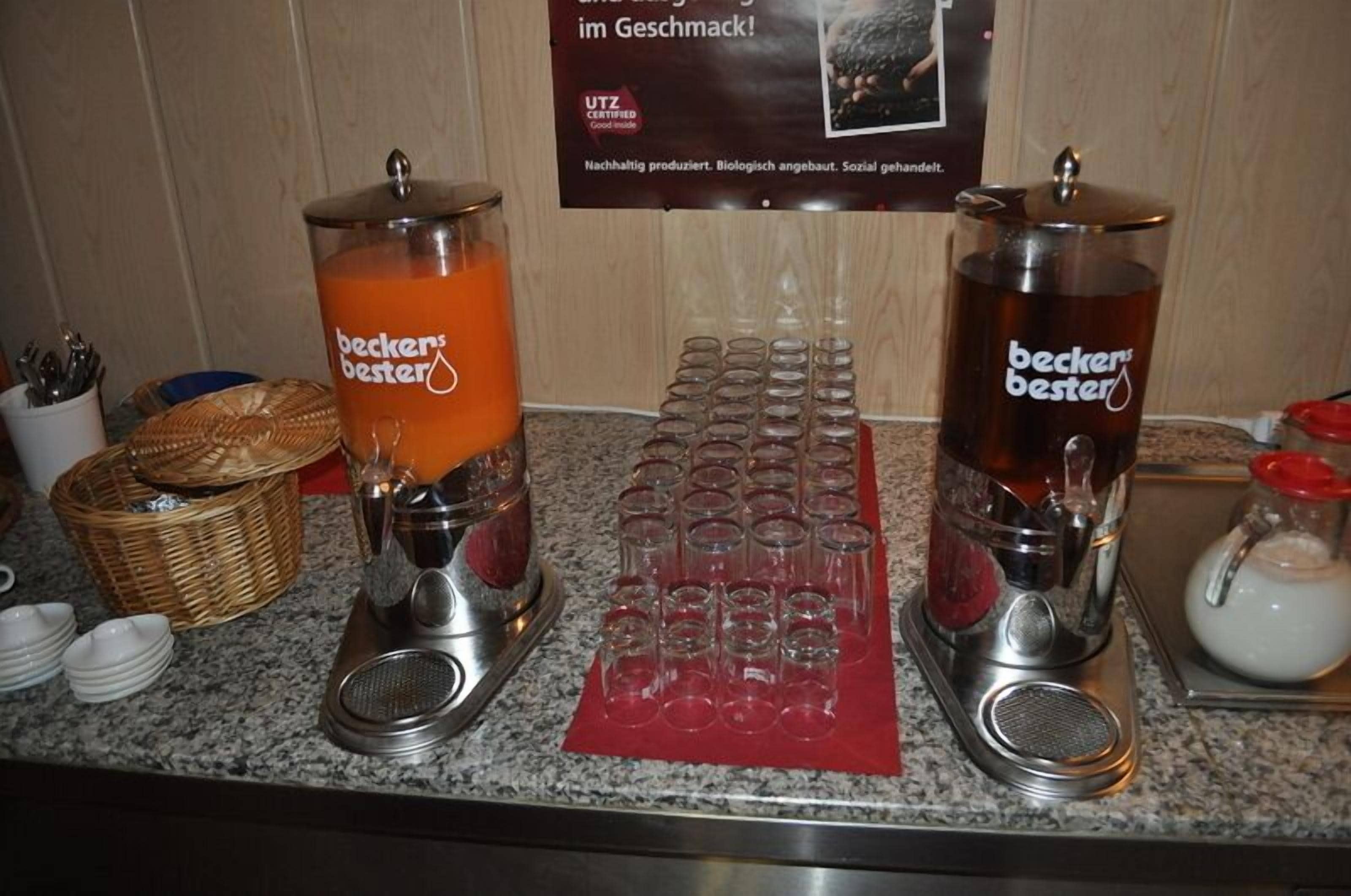 Un buffet avec deux distributeurs de boissons étiquetés « Beckers Bester » et un plateau rempli de verres vides.