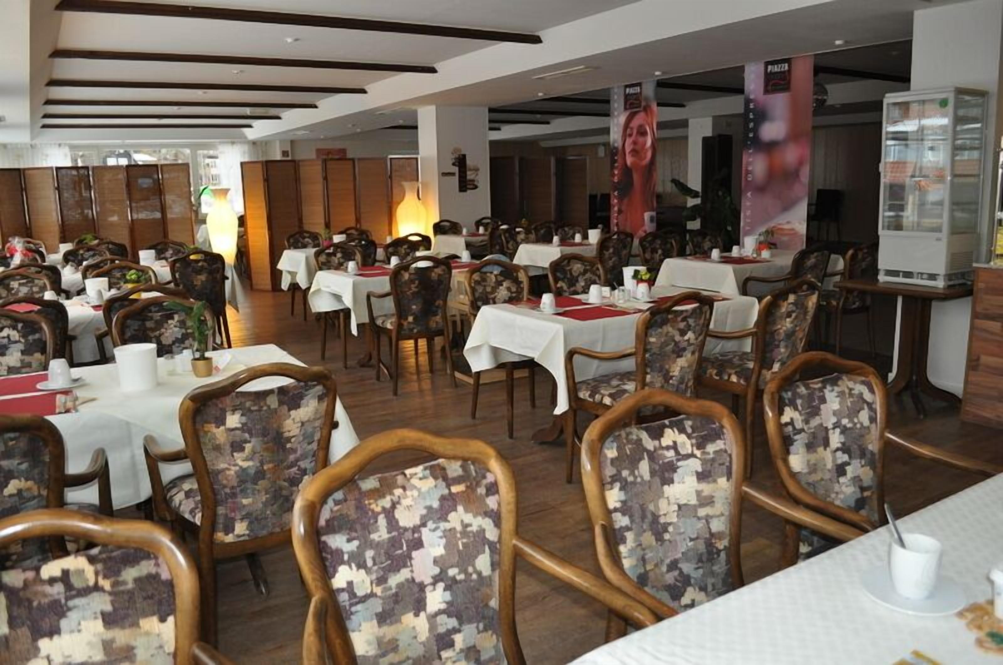 Un restaurante con varias mesas y sillas, algunas con tapicería floral.
