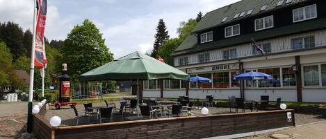 A hotel with outdoor seating, a swing set, and a flag.