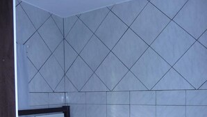 A bedroom with a bed, a ceiling fan, and a tiled wall. - Casa Nunes (Florianópolis)