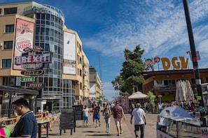 A bustling street with outdoor seating and various signs for restaurants and bars.