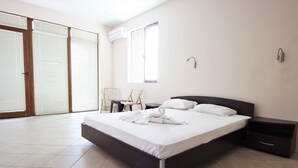 A spacious bedroom with a large bed, a bedside table, a chair, and a window.
