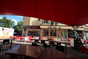 An outdoor seating area with tables and chairs, a sign for 'SUSI BAR', and a 'Pasta bar' sign.