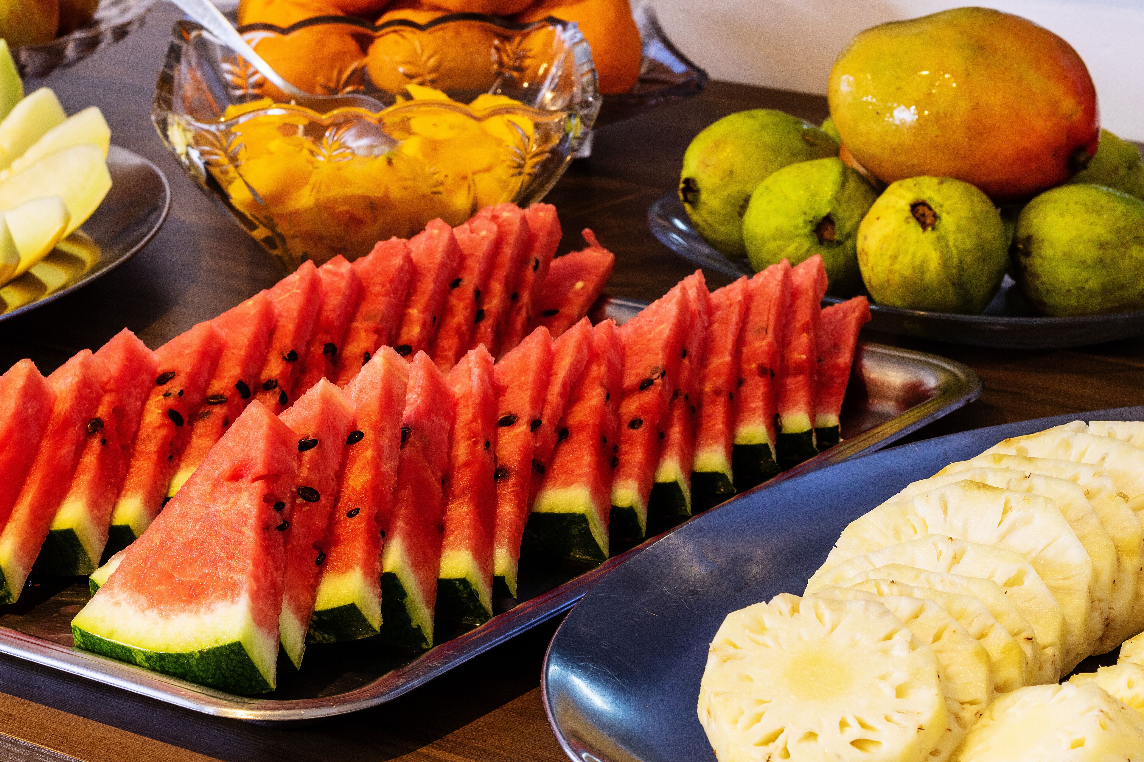 Una mesa con varias frutas, incluyendo sandía, piña y guayaba.
