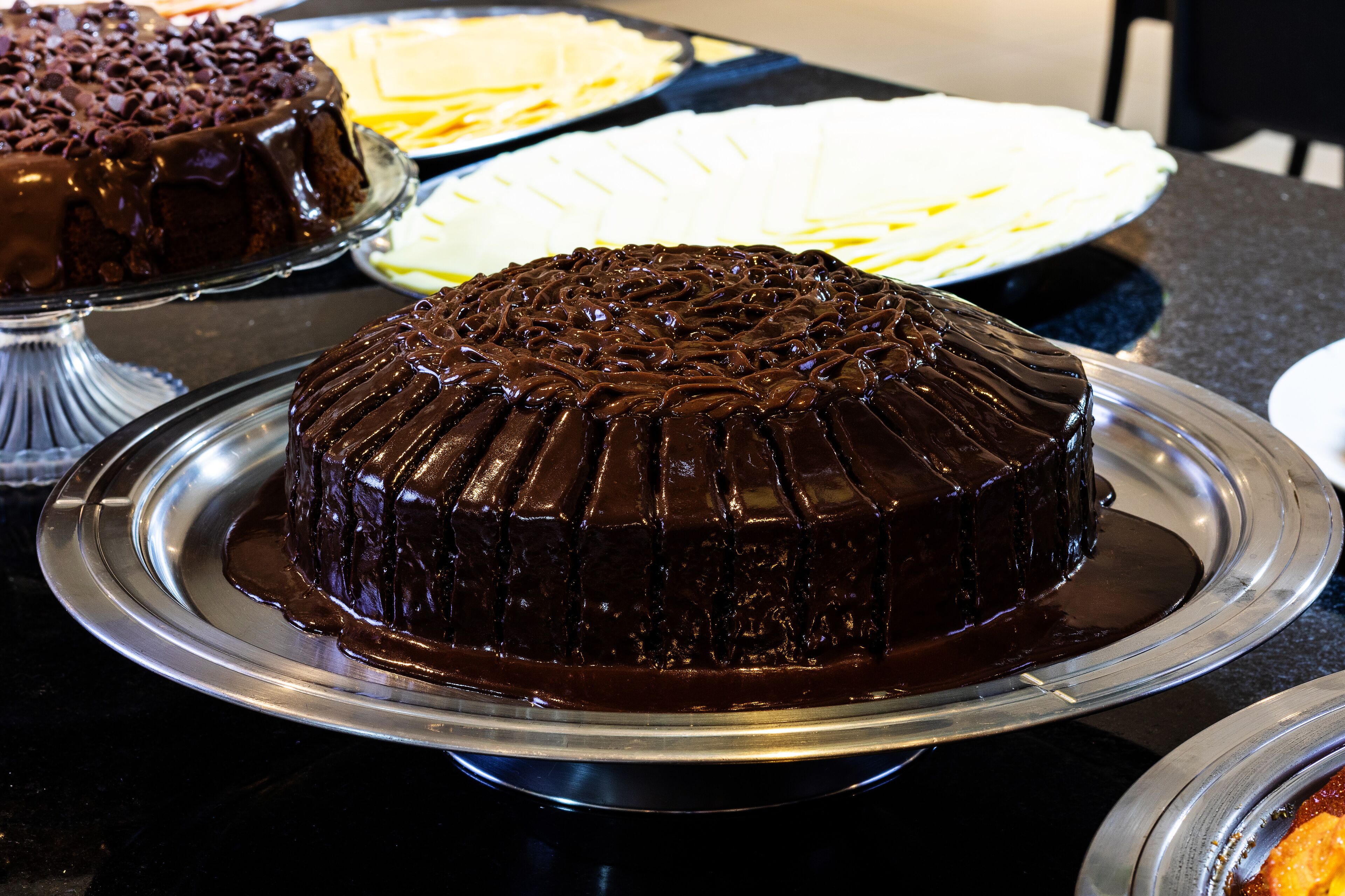 A chocolate cake on a silver cake stand.