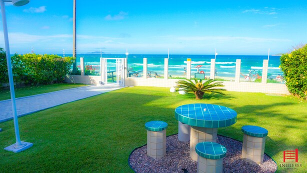 A well-maintained outdoor area with a pathway leading to a seating area with a table and chairs, surrounded by greenery and a view of the ocean.