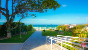 A paved pathway leading to a beach with a view of the ocean.