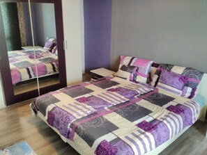 A bedroom with a bed, a bedside table, a mirror, and a wardrobe. - Apartmán Trutnov (Trutnov)