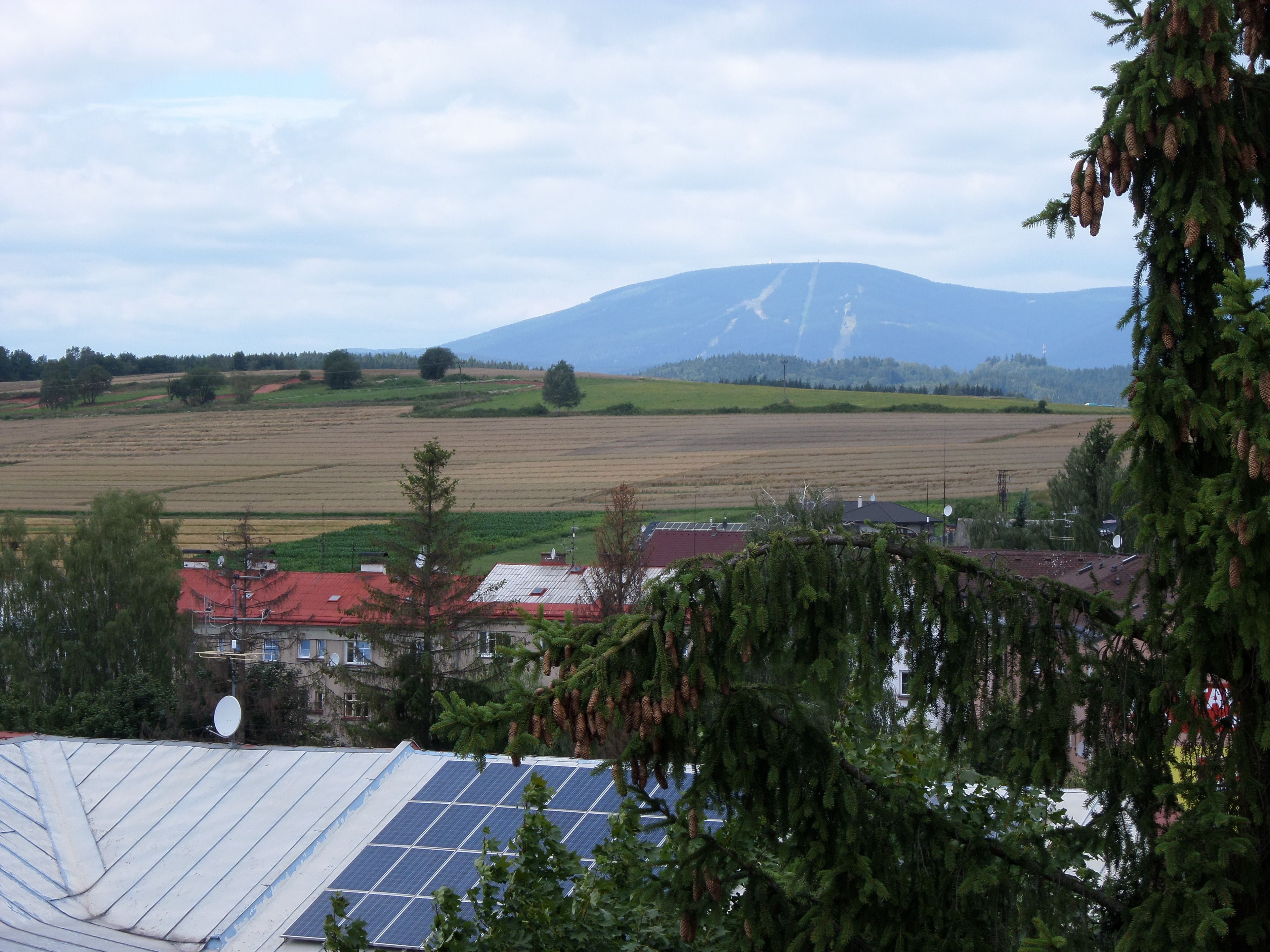 A rural landscape with fields, a mountain, and a building with solar panels.
