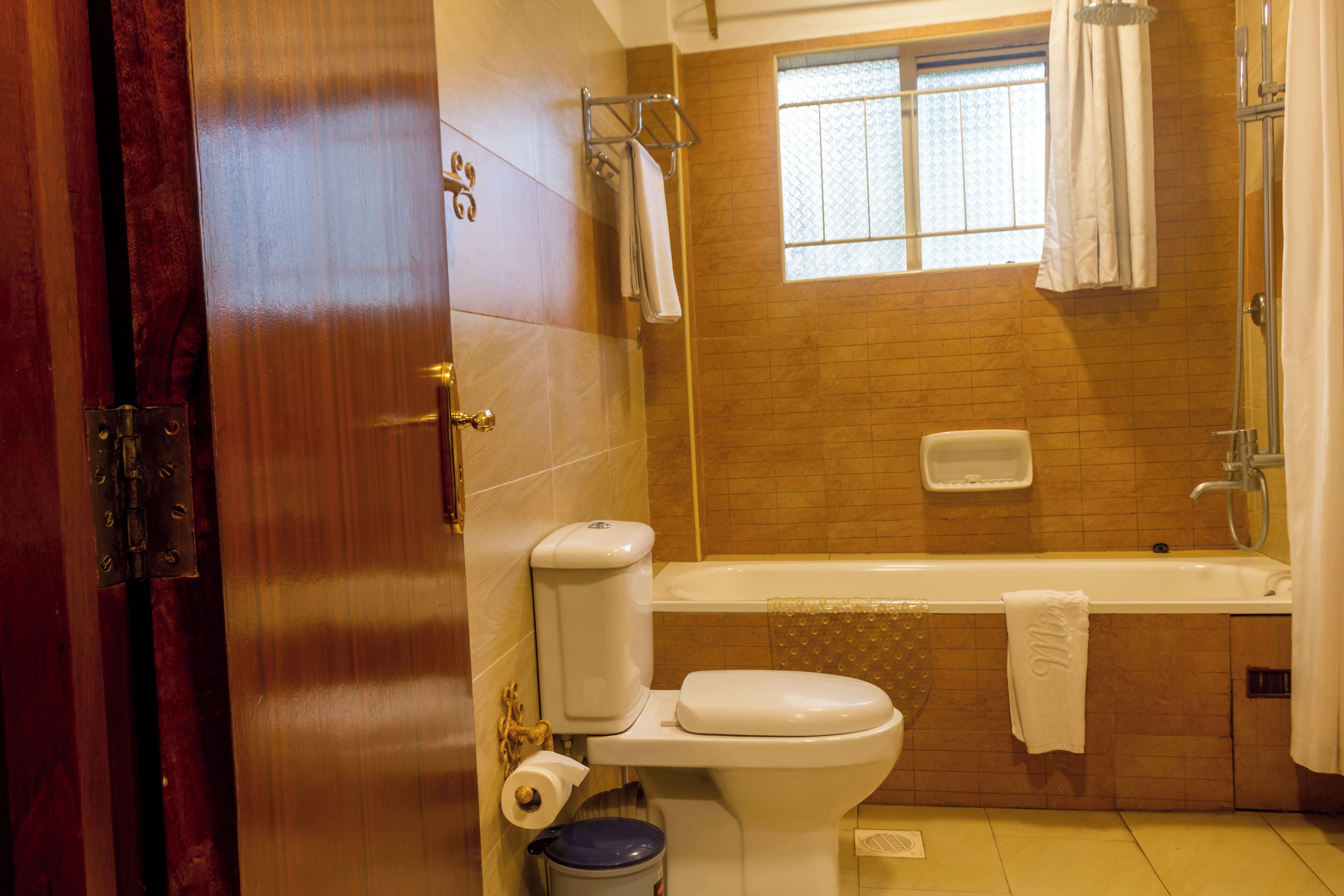 A bathroom with a toilet, a bathtub, and a window.