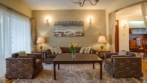 A cozy living room with a sofa set, a coffee table, and a painting on the wall. There are lamps on either side of the sofa and a vase with flowers on the coffee table. - Mimosa Court Apartments (Nairobi)