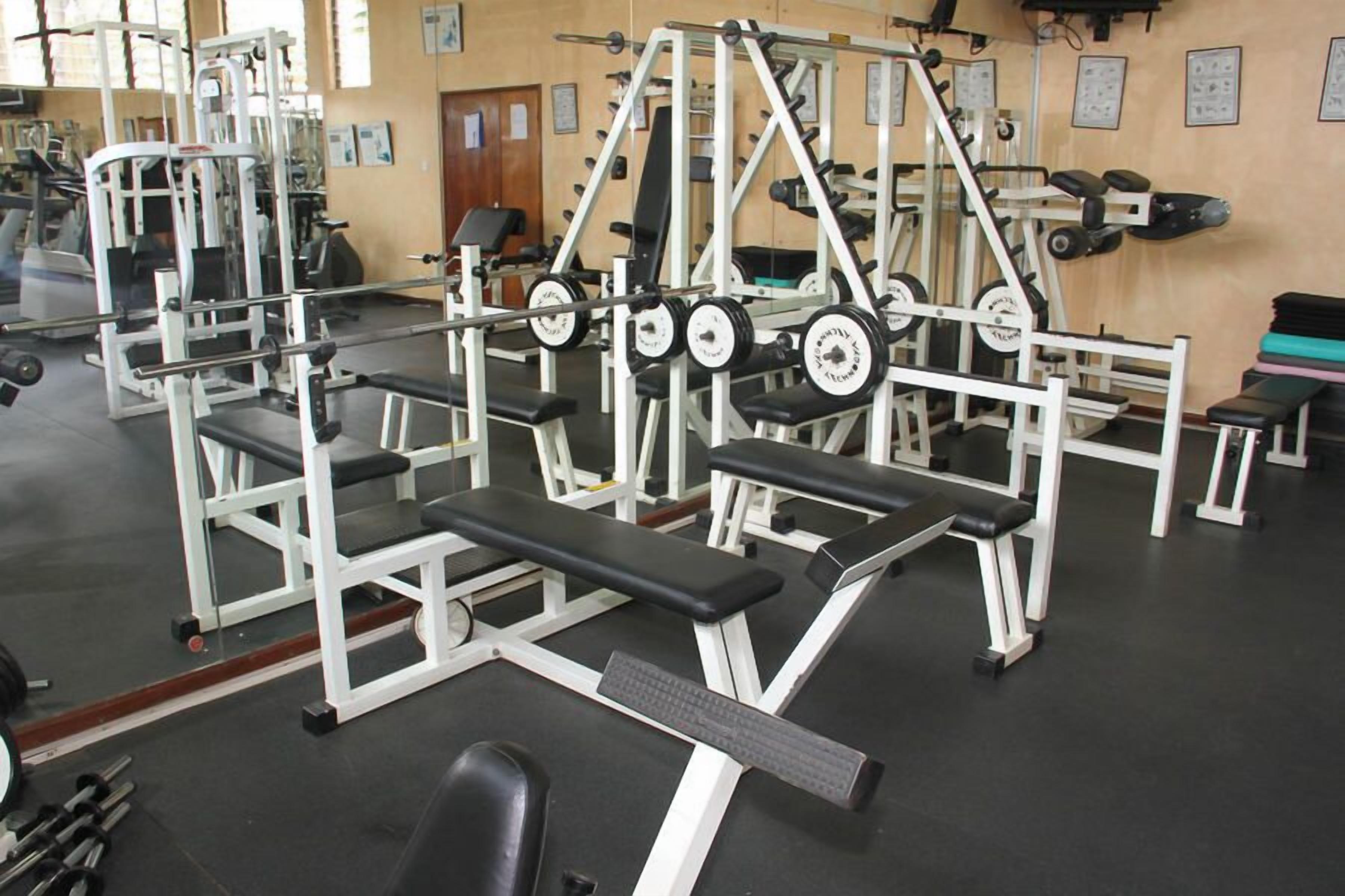 Une salle de sport équipée de matériel de musculation, de bancs et de tapis de course.