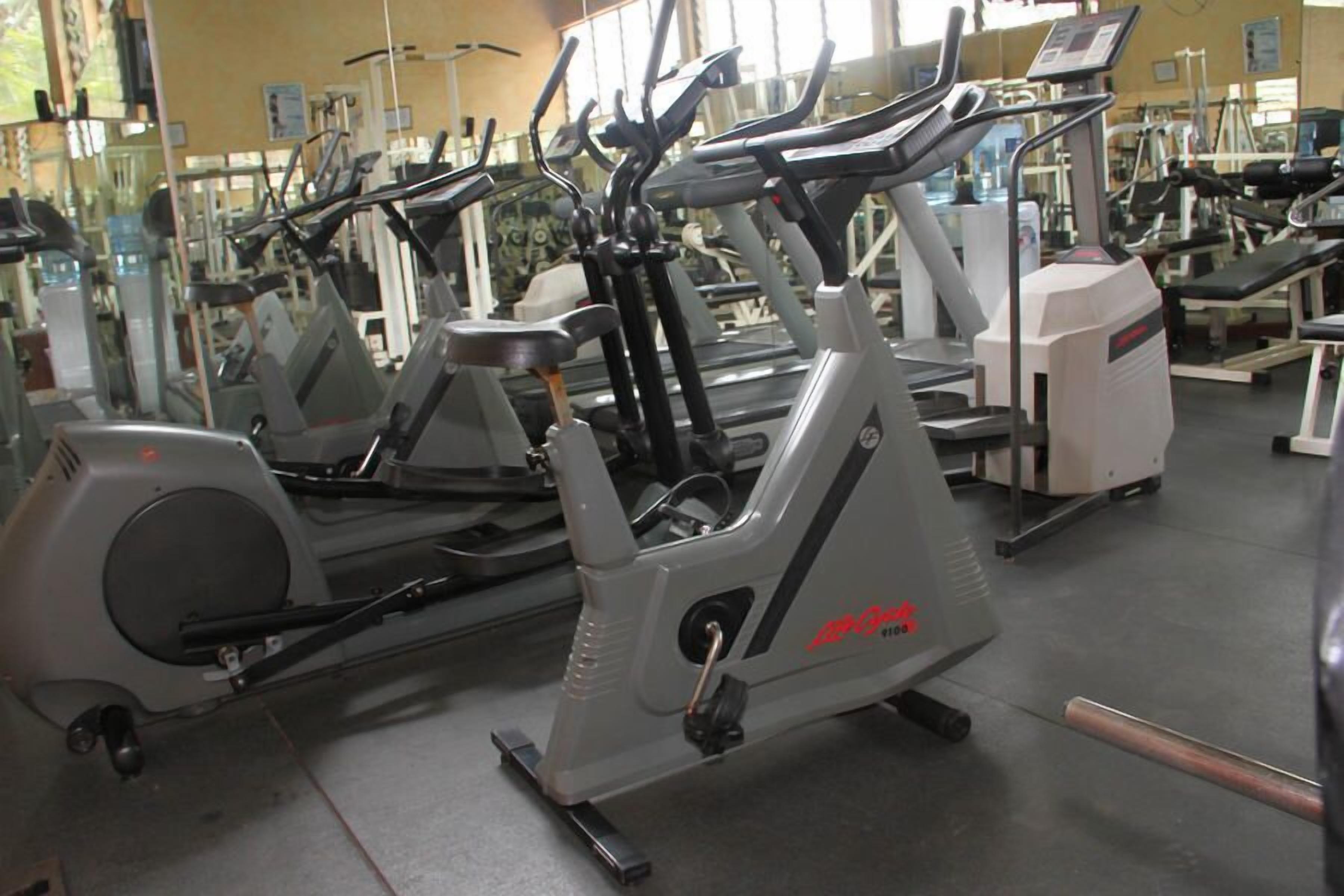 Un gimnasio con varias máquinas de cardio, incluyendo cintas de correr y elípticas.