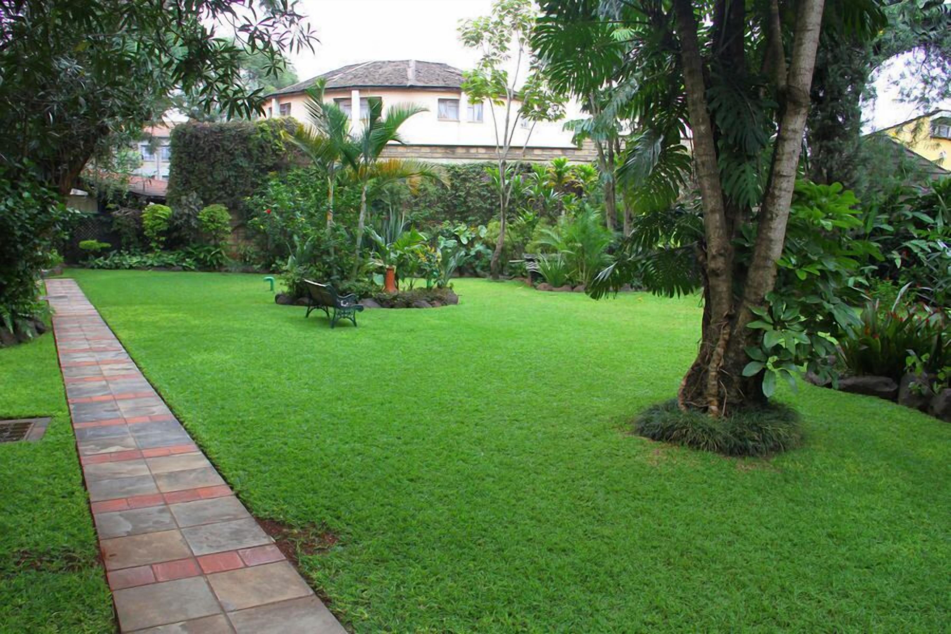 A well-maintained garden with a stone pathway leading to a house.