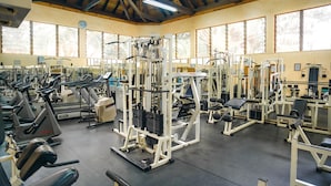 A gym with various exercise machines, large windows, and a wooden ceiling. - Mimosa Court Apartments (Nairobi)