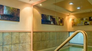 A modern bathroom with a glass-enclosed jacuzzi, beige tiled walls, and artwork on the walls. - Mimosa Court Apartments (Nairobi)