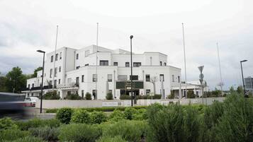 Un edificio moderno de fachada blanca, con numerosas ventanas y un letrero que indica un hotel.