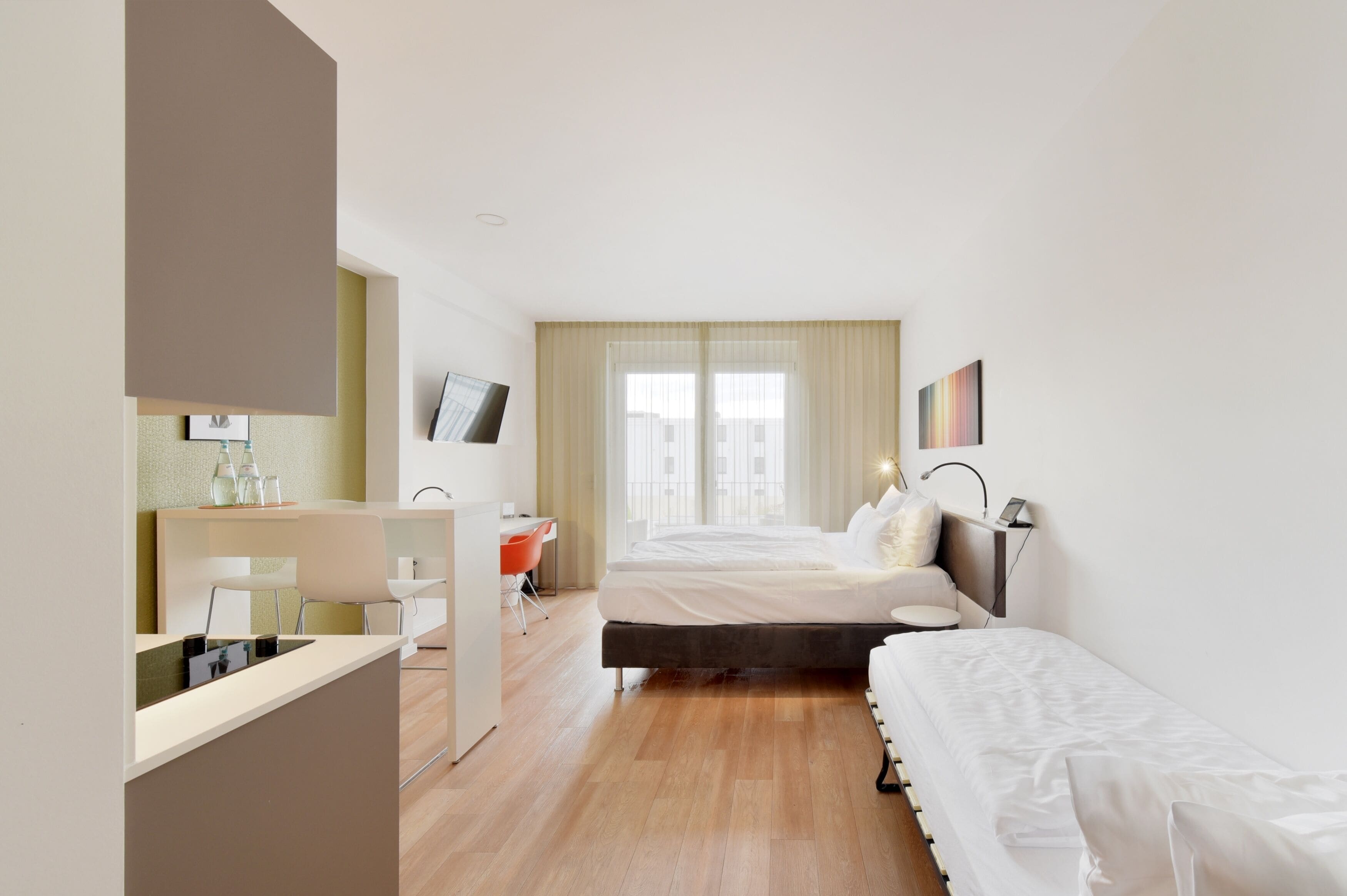 Quarto de hotel moderno com cama, mesa de cabeceira e escrivaninha com cadeira.