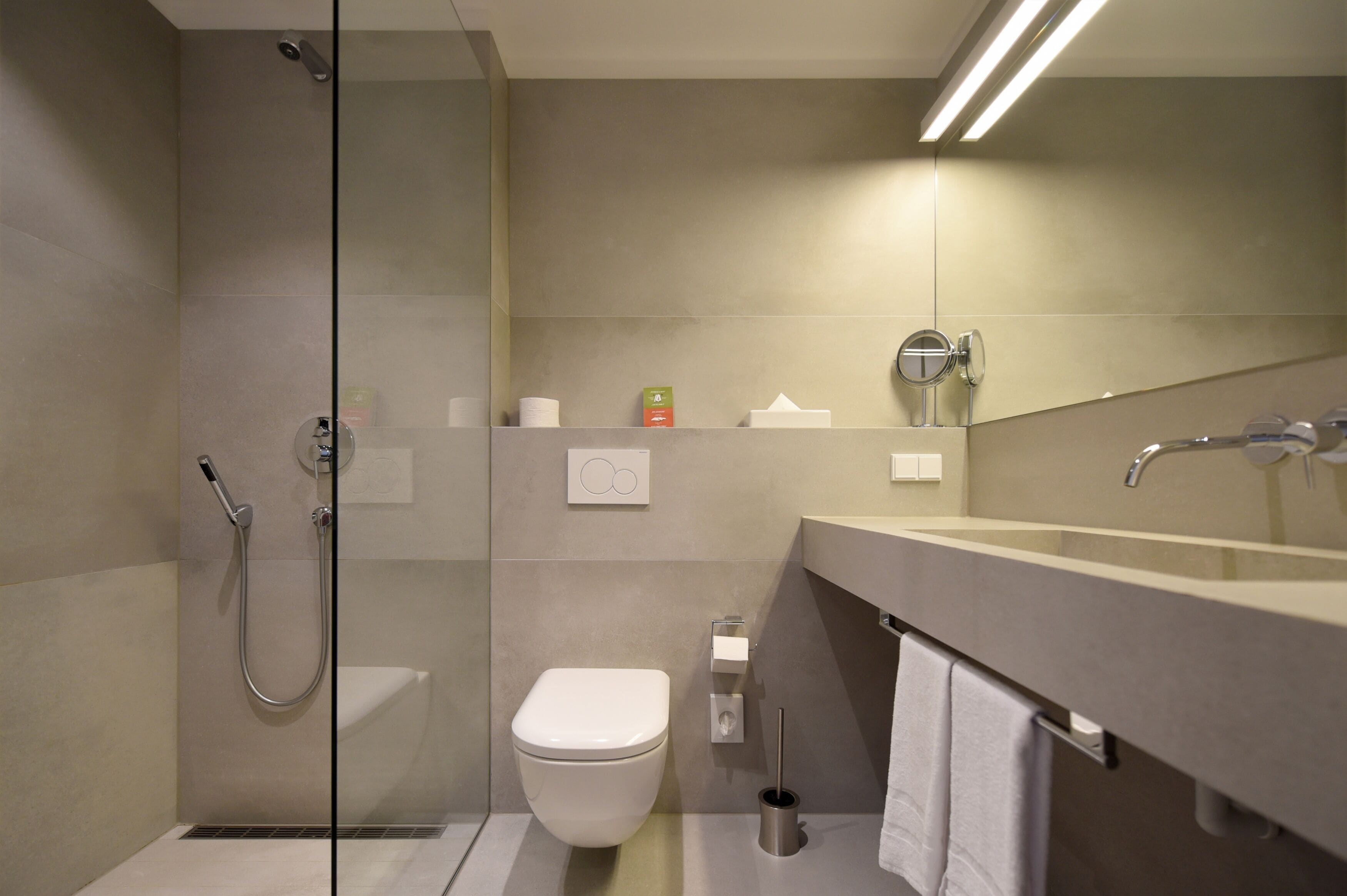Une salle de bain moderne avec une douche à parois de verre, des toilettes, un lavabo avec un miroir et un porte-serviettes.