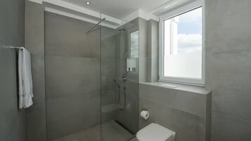 Un baño moderno con ducha de vidrio, inodoro y ventana que proporciona luz natural.