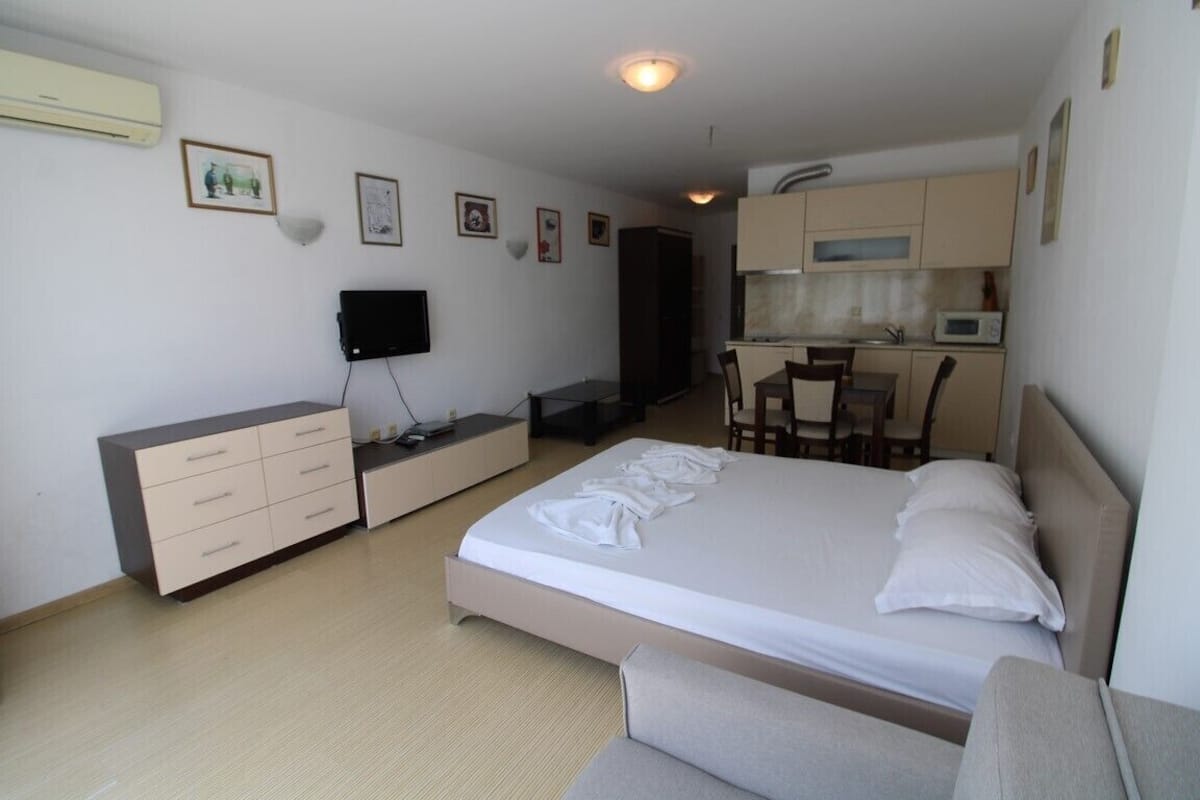 Une chambre d’hôtel comprenant un lit, un bureau avec une chaise, une télévision, une armoire et une kitchenette.