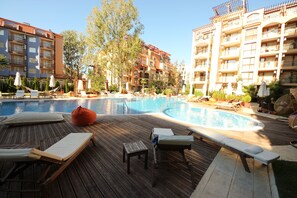 Ein Poolbereich mit Liegestühlen, einer Holzterrasse und einem Schwimmbecken.