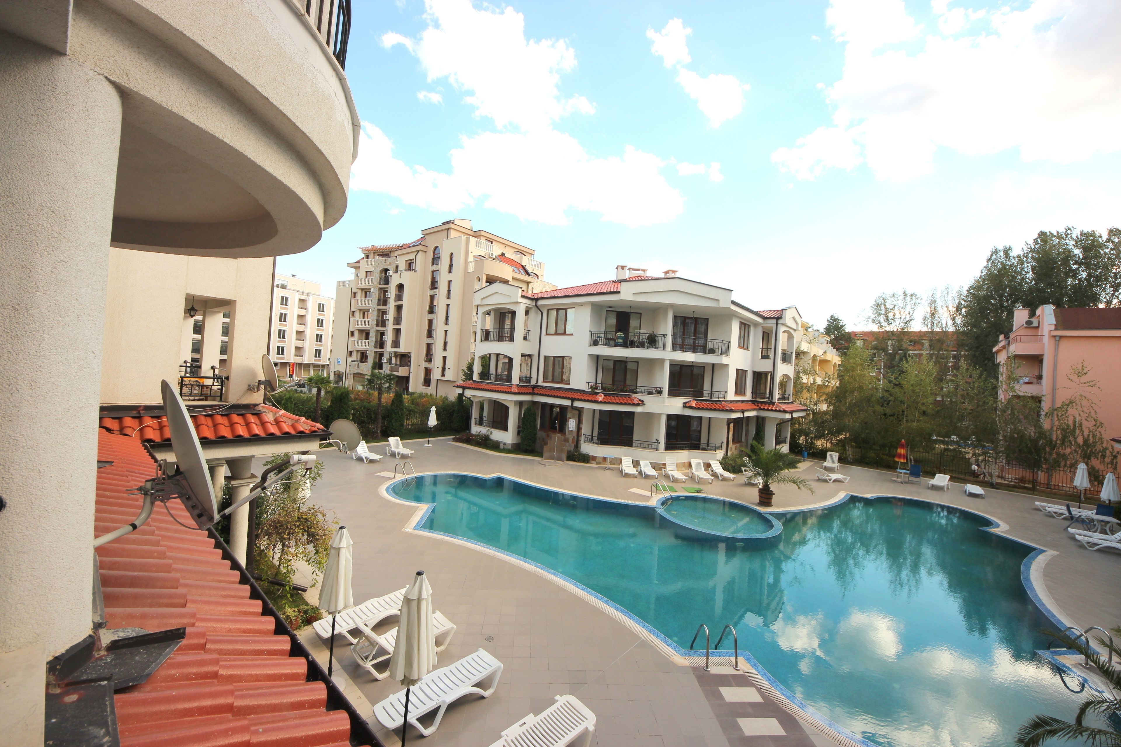 A swimming pool with lounge chairs and a view of surrounding buildings.
