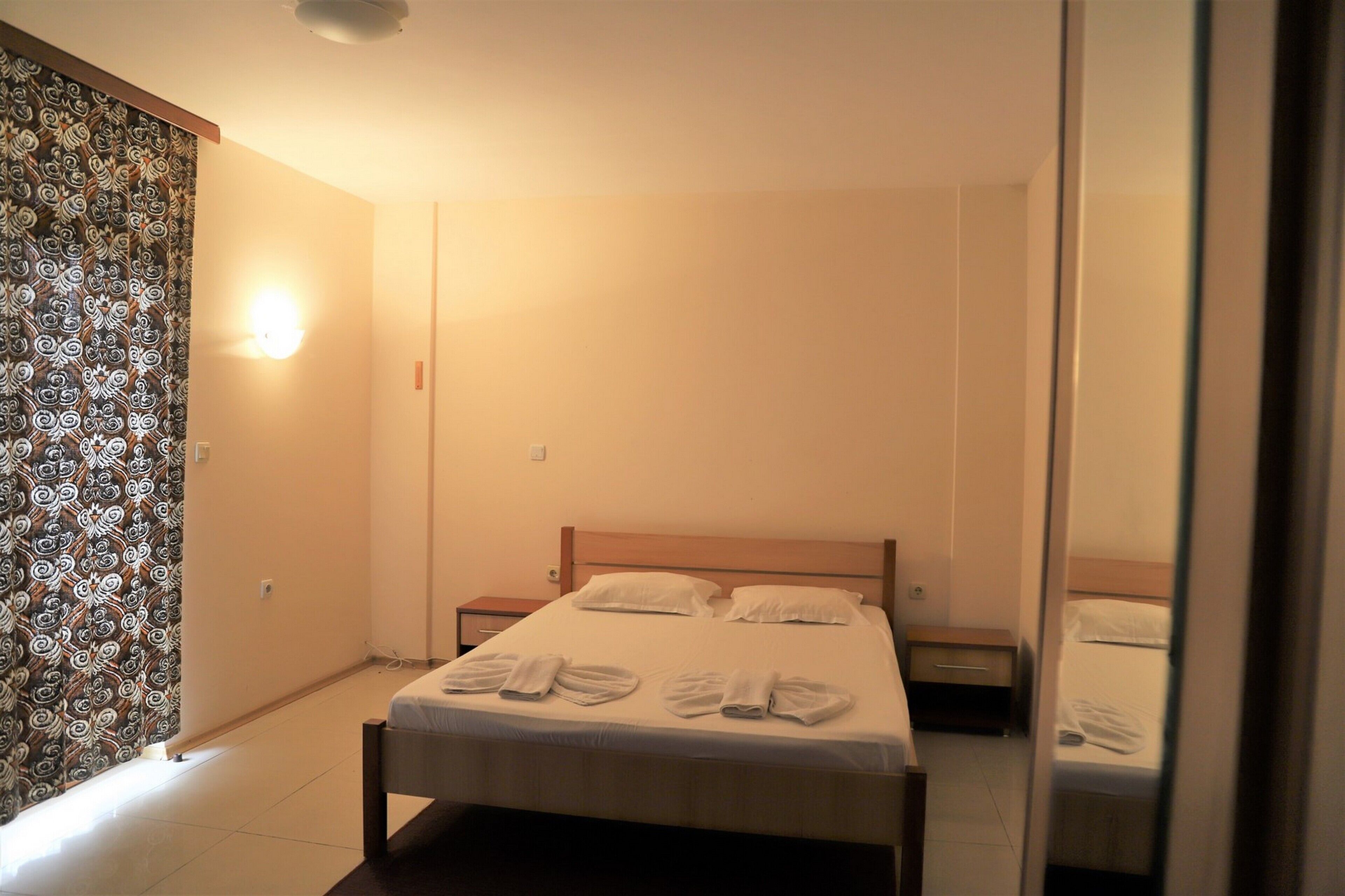 Habitación de hotel con una cama, dos mesitas de noche y un espejo.