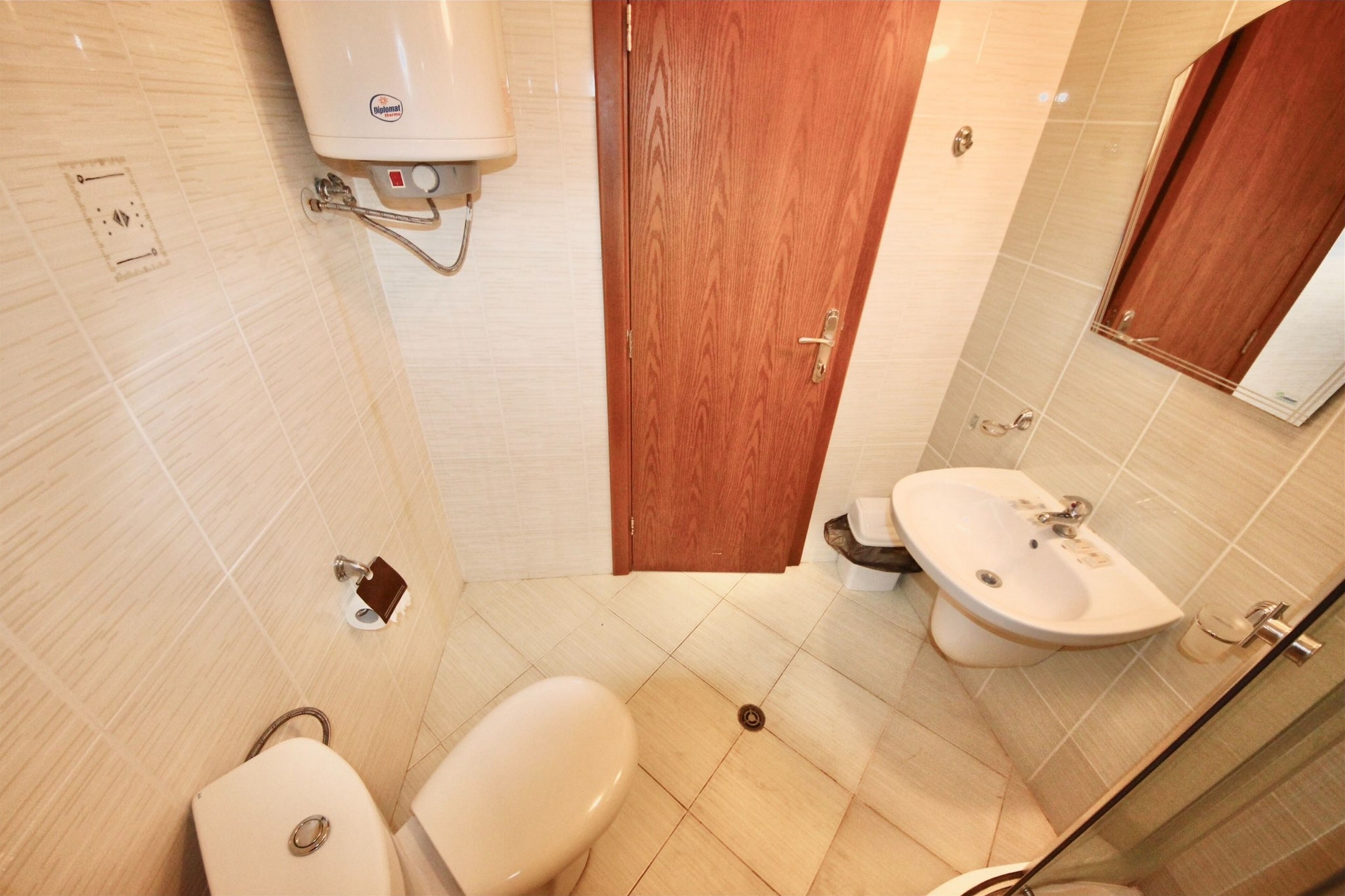 Une petite salle de bain avec des toilettes, un lavabo et une porte en bois.