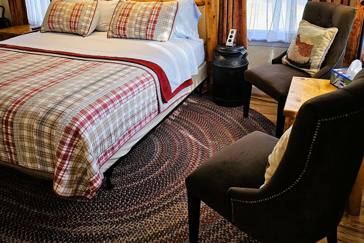 A hotel room with a large bed, two bedside lamps, a chair, a small table, and a rug.