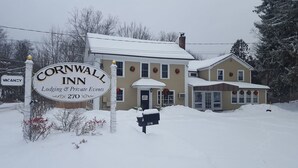Un edificio de dos pisos con un letrero que indica Cornwall Inn, que cuenta con un porche delantero y un buzón.