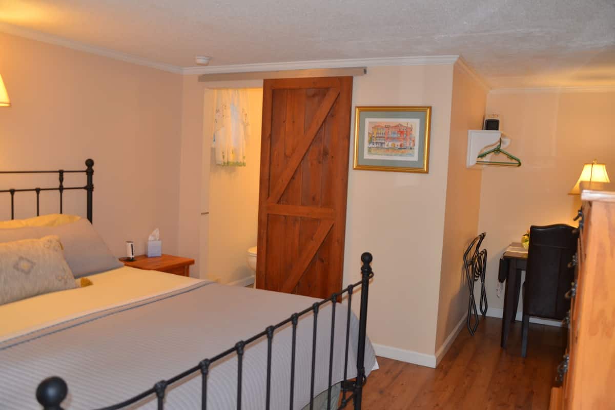 A bedroom with a bed, bedside table, and a wooden door.